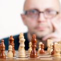 围棋教练在木质棋盘前摆谱讲解围棋ai推荐点的场景，暖色台灯下棋形清晰可见