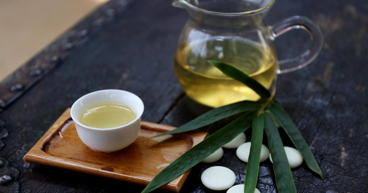 弈境围棋ai编辑部工作台场景，深色木质桌面上摊开的围棋棋盘与笔记本电脑并排放置，暖金色台灯从侧面照下，屏幕上是棋局分析界面，整体氛围安静专注